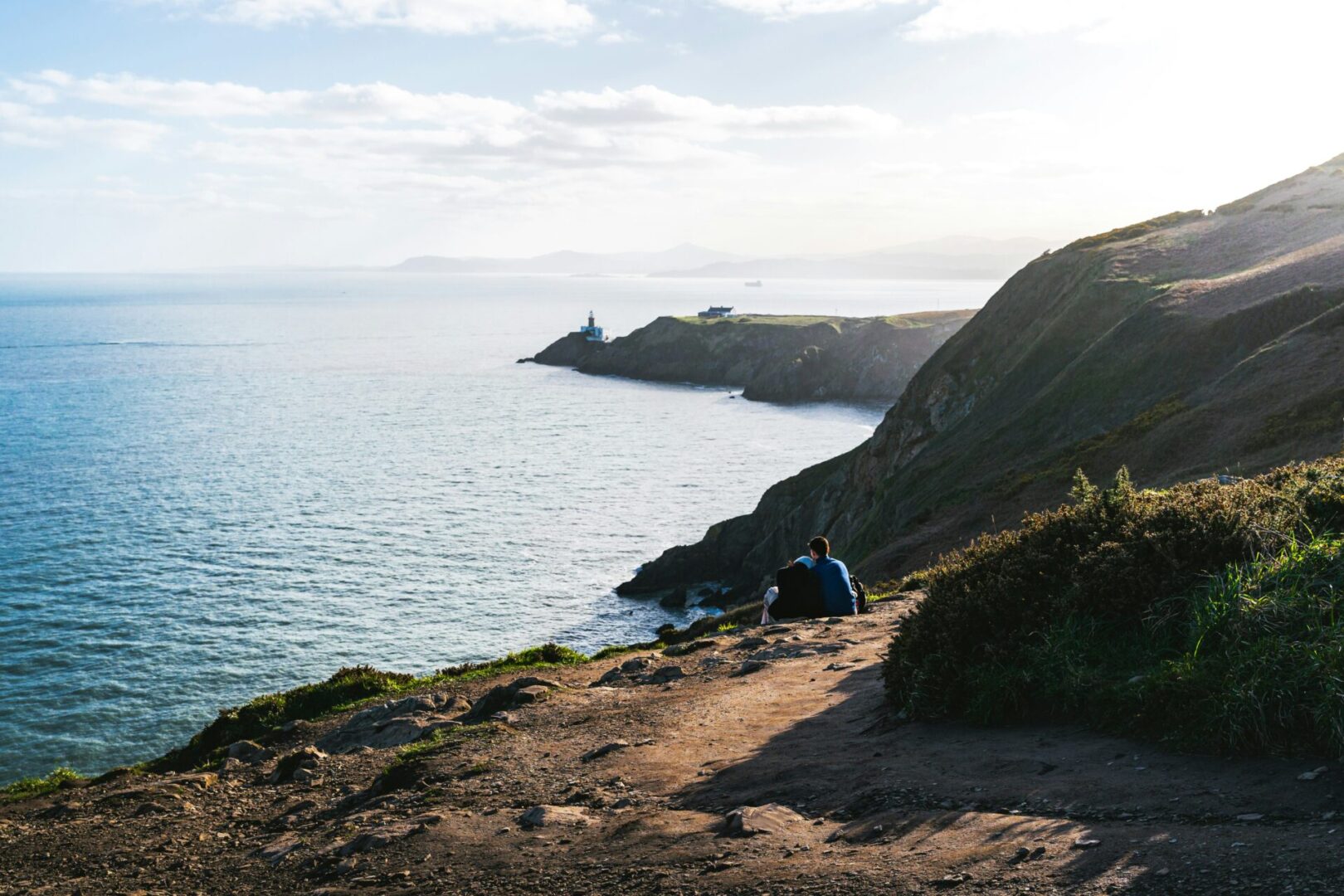 A tent is pitched on the side of a cliff overlooking the ocean.